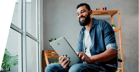 Man smiling and typing on his I-pad in his house