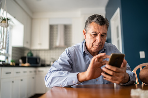 a person looking at a phone while sitting at a kitchen table