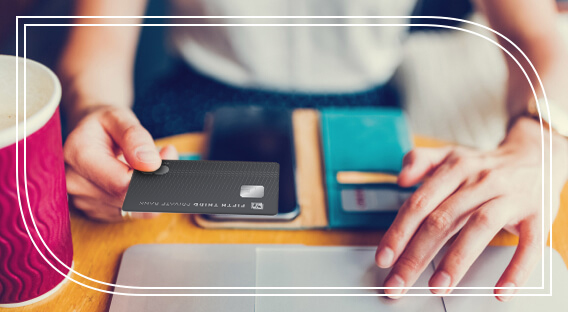 A person holding a Fifth Third Private Bank Mastercard above their laptop.